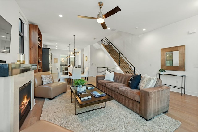 living room with ceiling fan with notable chandelier and light hardwood / wood-style floors