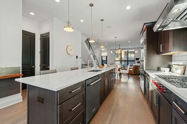 kitchen with appliances with stainless steel finishes, a large island, ventilation hood, and hanging light fixtures