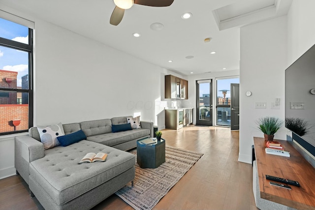 living room with ceiling fan, plenty of natural light, and wood-type flooring