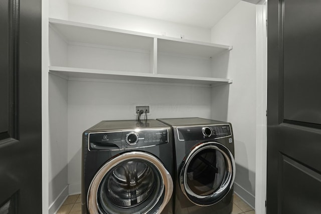 clothes washing area with washing machine and dryer and light tile patterned floors