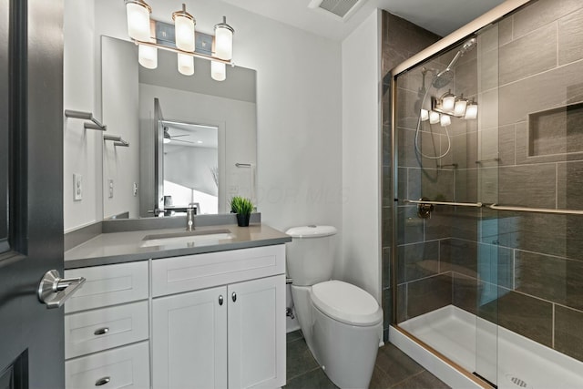 bathroom with tile patterned floors, toilet, vanity, a shower with door, and ceiling fan