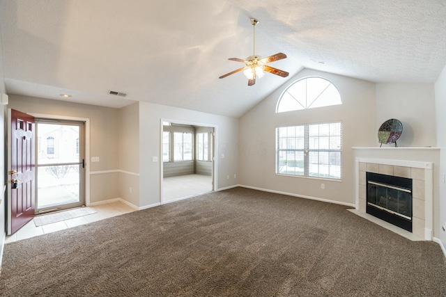 unfurnished living room featuring a textured ceiling, lofted ceiling, a fireplace, ceiling fan, and light colored carpet