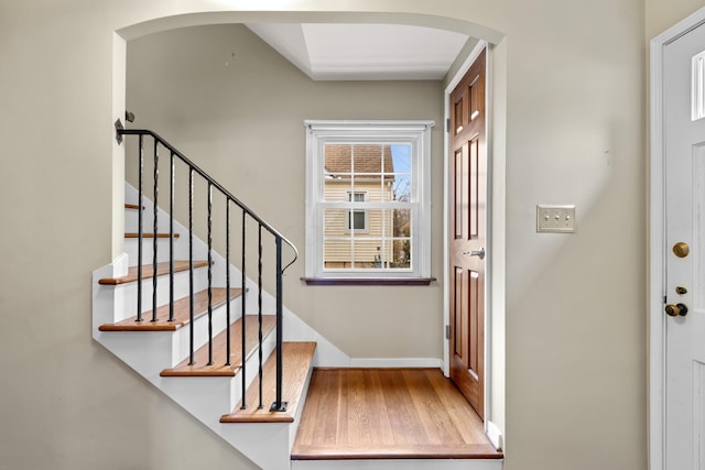 entrance foyer featuring arched walkways, stairway, and baseboards