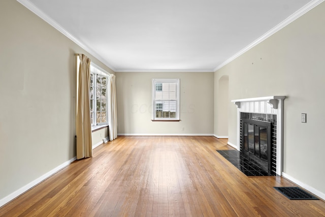 unfurnished living room featuring visible vents, baseboards, a fireplace with flush hearth, wood-type flooring, and ornamental molding