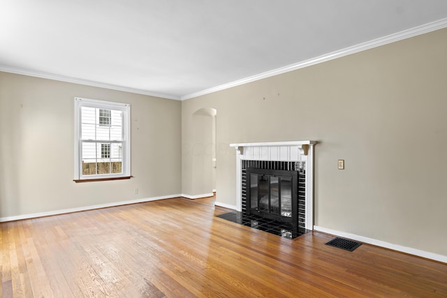 unfurnished living room featuring baseboards, a fireplace, ornamental molding, and hardwood / wood-style floors