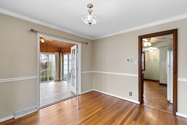 unfurnished room with ornamental molding, visible vents, baseboards, and hardwood / wood-style flooring