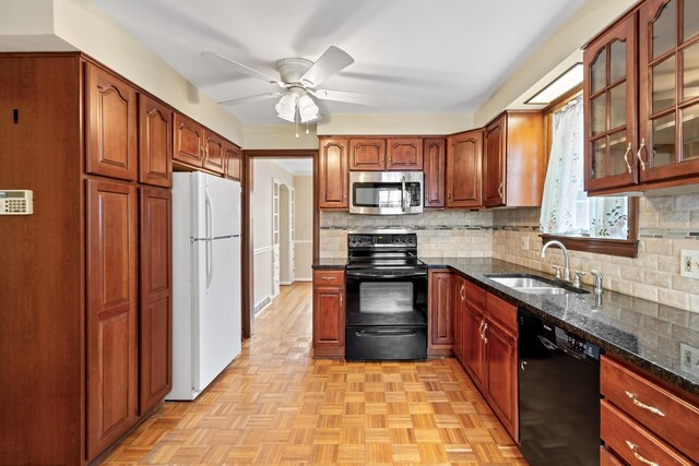 kitchen featuring tasteful backsplash, glass insert cabinets, a sink, dark stone counters, and black appliances