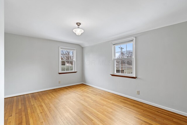 spare room with baseboards, a healthy amount of sunlight, and hardwood / wood-style floors