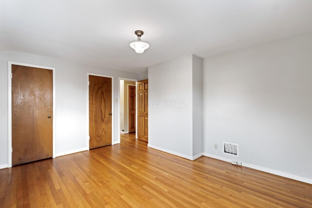 unfurnished bedroom with light wood-style flooring, visible vents, and baseboards