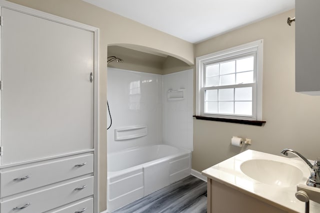 bathroom featuring bathtub / shower combination, wood finished floors, vanity, and baseboards