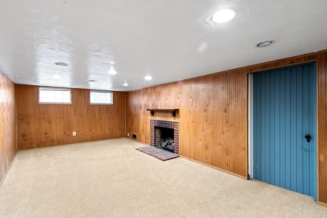 basement featuring carpet floors, a brick fireplace, wooden walls, and a textured ceiling