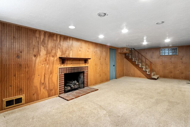 unfurnished living room featuring carpet, a fireplace, visible vents, and stairs