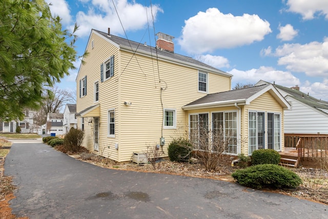 exterior space featuring a sunroom, a chimney, and a wooden deck