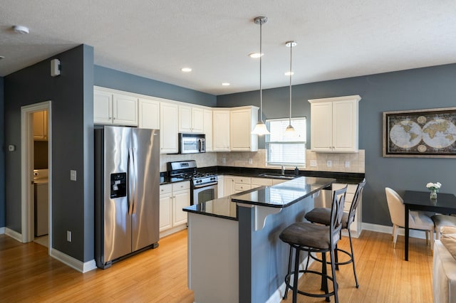 kitchen featuring decorative light fixtures, sink, white cabinets, and stainless steel appliances