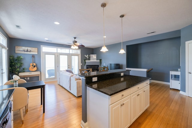 kitchen featuring white cabinetry, dark stone countertops, dishwasher, hanging light fixtures, and light hardwood / wood-style flooring