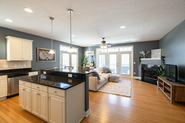 kitchen featuring decorative light fixtures, backsplash, dishwasher, a kitchen island, and light hardwood / wood-style flooring