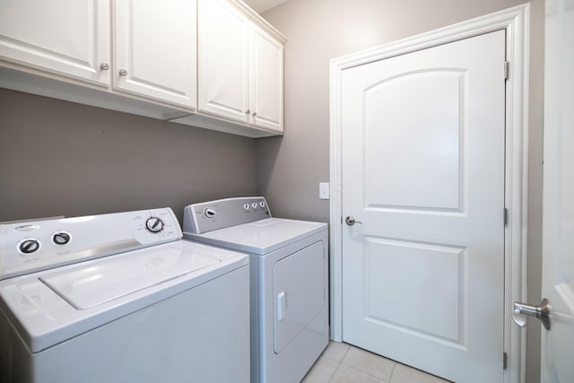 clothes washing area with washing machine and dryer, cabinets, and light tile patterned floors