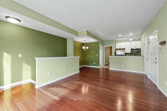 unfurnished living room with a notable chandelier and dark hardwood / wood-style flooring