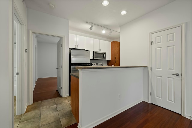 kitchen with kitchen peninsula, white cabinets, and tile patterned floors