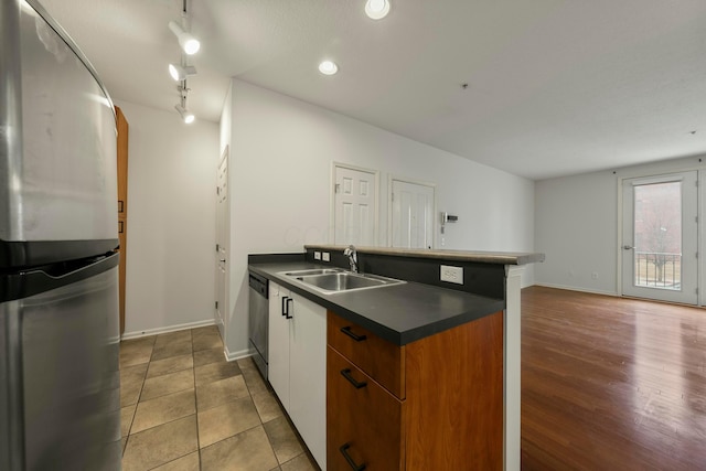 kitchen with white cabinetry, kitchen peninsula, stainless steel appliances, sink, and track lighting