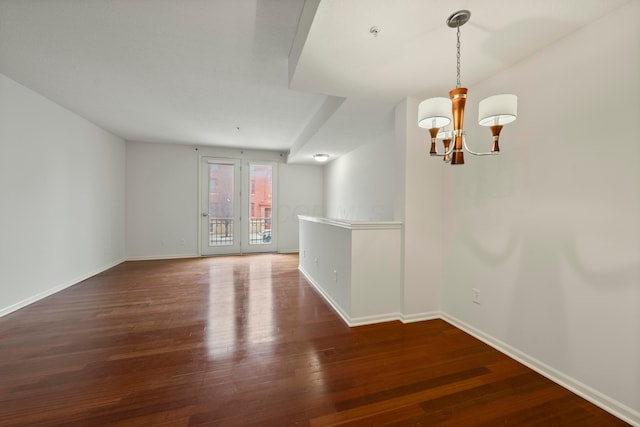 spare room with dark hardwood / wood-style floors and an inviting chandelier