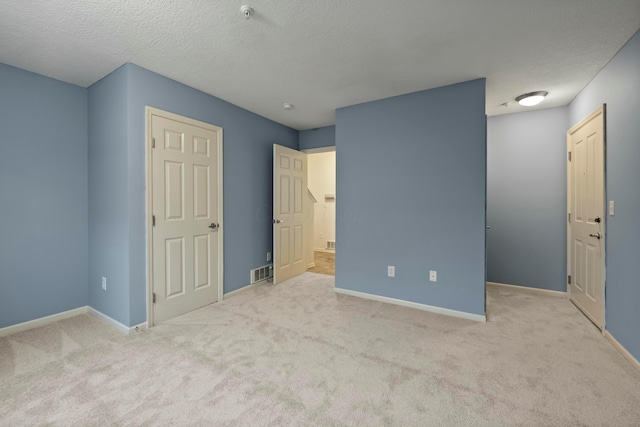 unfurnished bedroom with light carpet and a textured ceiling