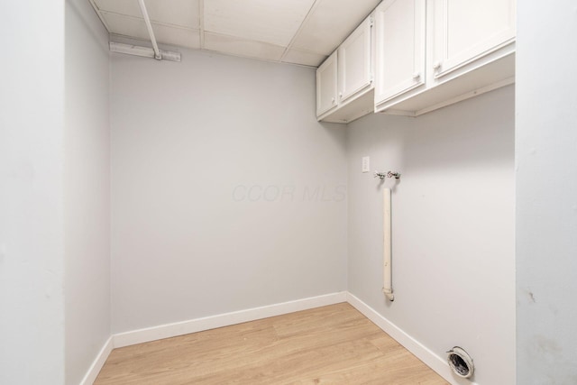 washroom with hookup for a washing machine, cabinets, and light wood-type flooring