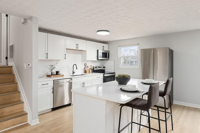 kitchen featuring white cabinetry, sink, light hardwood / wood-style flooring, and appliances with stainless steel finishes