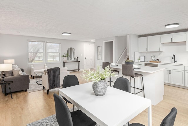 dining area with sink, a textured ceiling, and light hardwood / wood-style floors