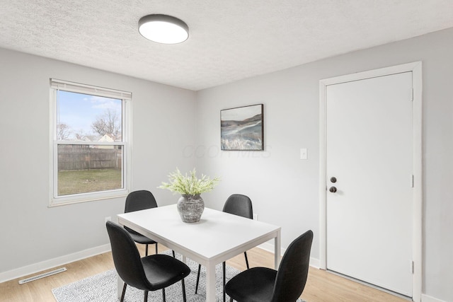 dining room with a textured ceiling and light wood-type flooring