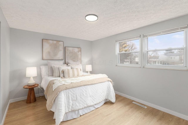 bedroom with a textured ceiling and light hardwood / wood-style floors