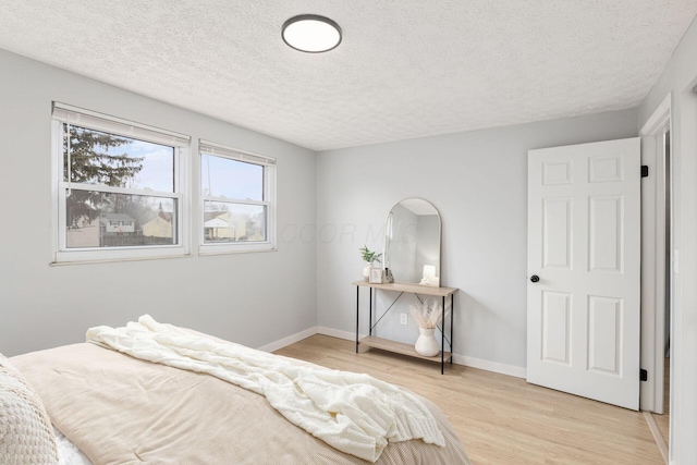 bedroom with light hardwood / wood-style floors and a textured ceiling