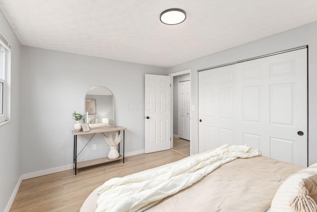 bedroom featuring a textured ceiling, light wood-type flooring, and a closet