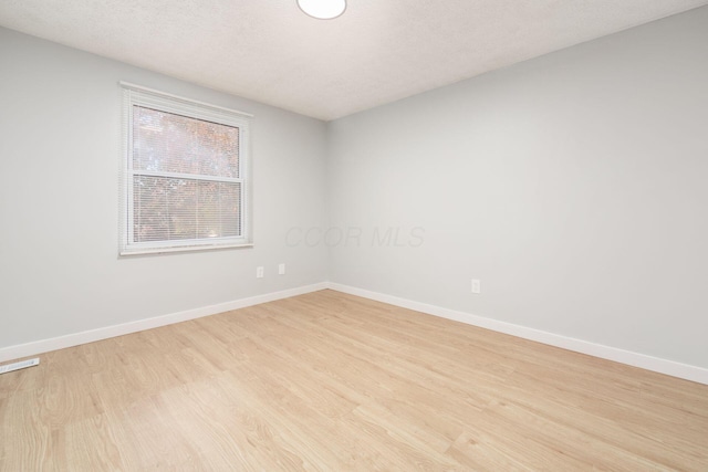 empty room featuring a textured ceiling and light hardwood / wood-style flooring