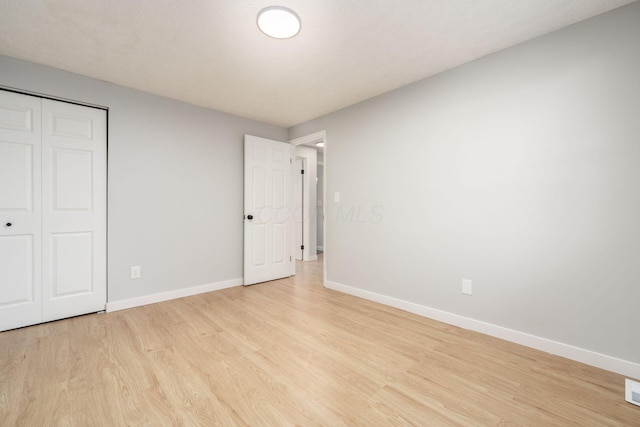 unfurnished bedroom with light wood-type flooring and a closet