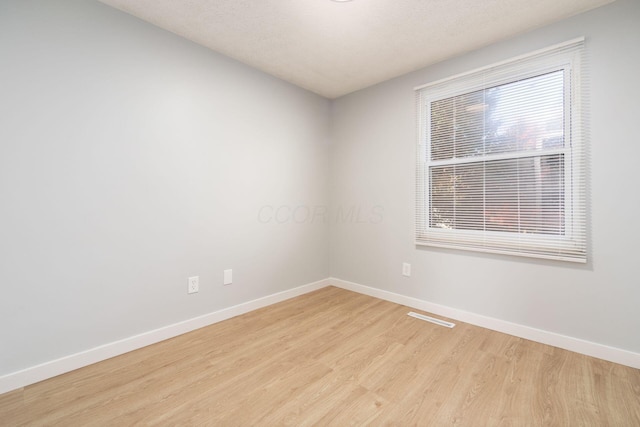 empty room with light hardwood / wood-style flooring and a textured ceiling