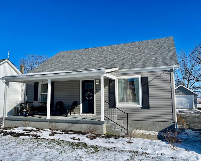 bungalow-style home featuring a garage, a porch, and an outbuilding