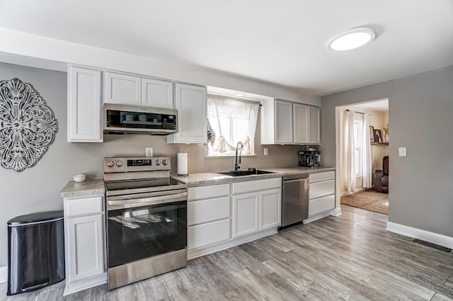 kitchen featuring sink, white cabinetry, stainless steel appliances, and light wood-type flooring