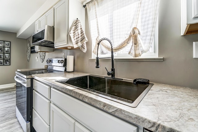 kitchen featuring sink, white cabinets, appliances with stainless steel finishes, and plenty of natural light