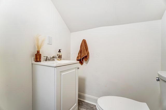 bathroom with toilet, vanity, and vaulted ceiling