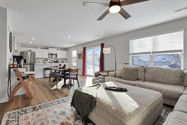 living room with ceiling fan and light hardwood / wood-style flooring