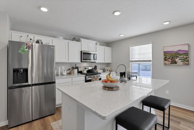 kitchen featuring white cabinetry, a center island with sink, and stainless steel appliances