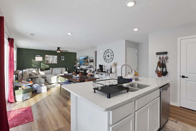 kitchen featuring white cabinets, dishwasher, light wood-type flooring, ceiling fan, and a center island with sink