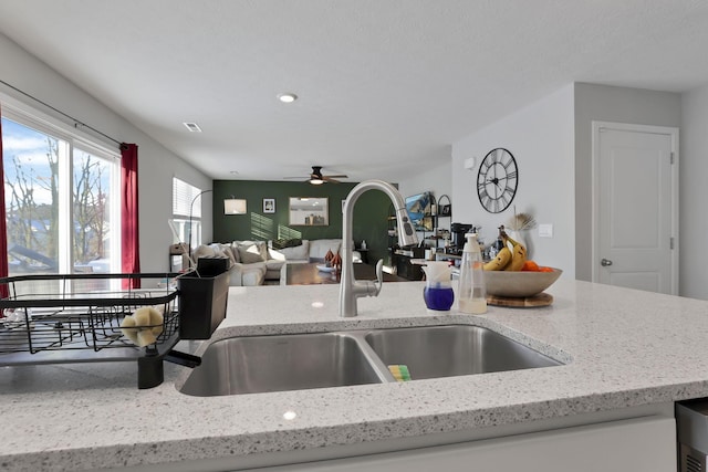 kitchen with light stone countertops, sink, and ceiling fan