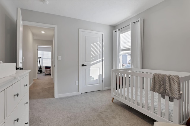 carpeted bedroom featuring a nursery area and multiple windows