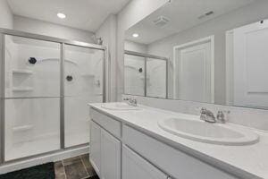 bathroom with a shower with shower door and vanity