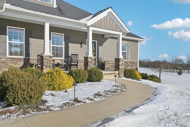 snow covered property entrance featuring covered porch