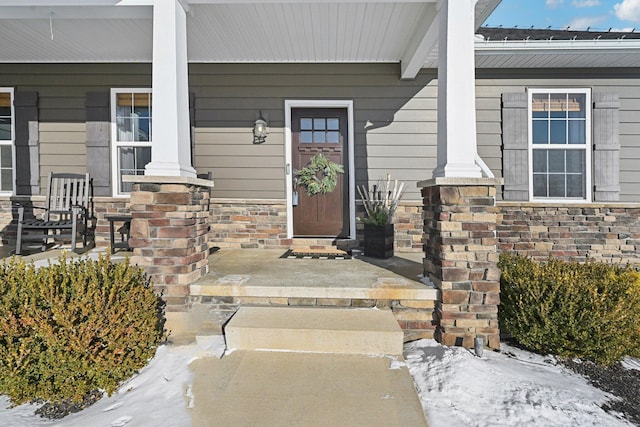 snow covered property entrance with covered porch