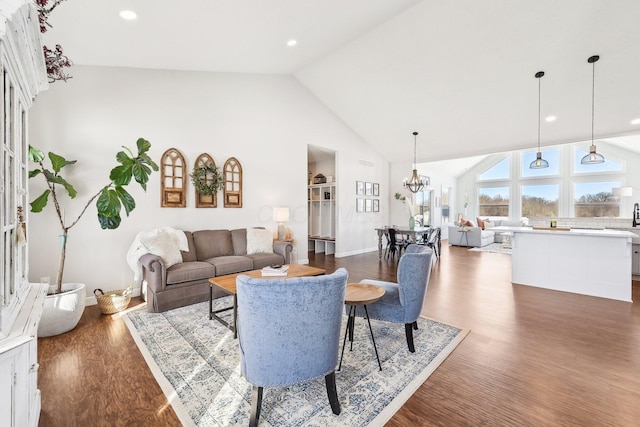 living room featuring dark wood-type flooring, high vaulted ceiling, and a notable chandelier