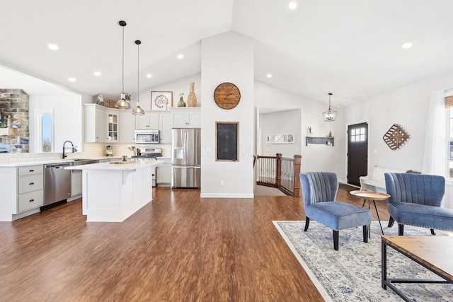 kitchen with decorative light fixtures, dark hardwood / wood-style floors, a kitchen island, stainless steel appliances, and decorative backsplash